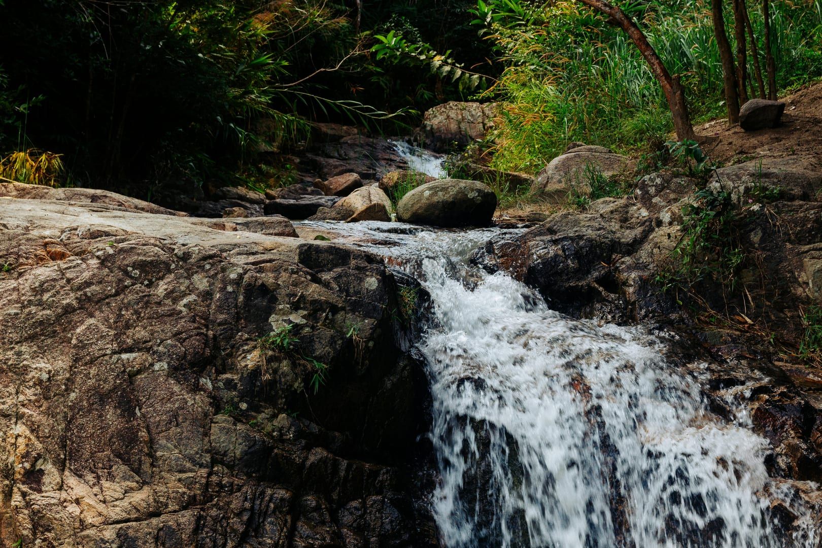 Waterfall flowing over rocks in lush jungle setting near Koh Samui hidden gem waterfall